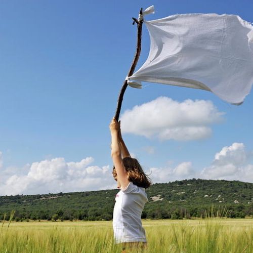 girl-holding-high-a-white-flag-in-wheat-field.jpg